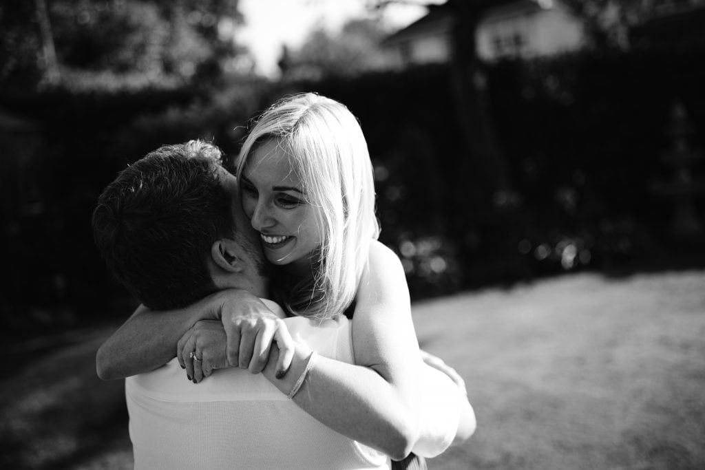 A black and white photo of a man hugging a woman.