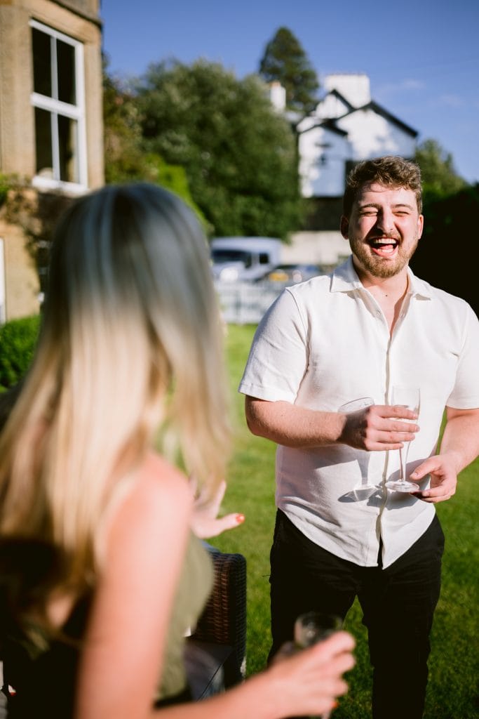 A man and woman laughing in the yard of a house.