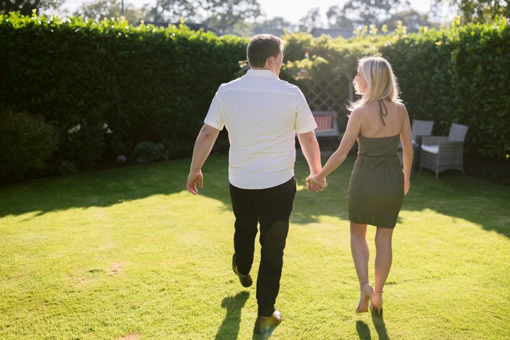 A couple holding hands in a grassy yard.