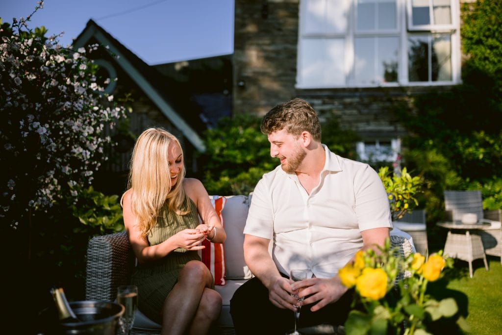 A man and woman sitting on a couch in a garden.