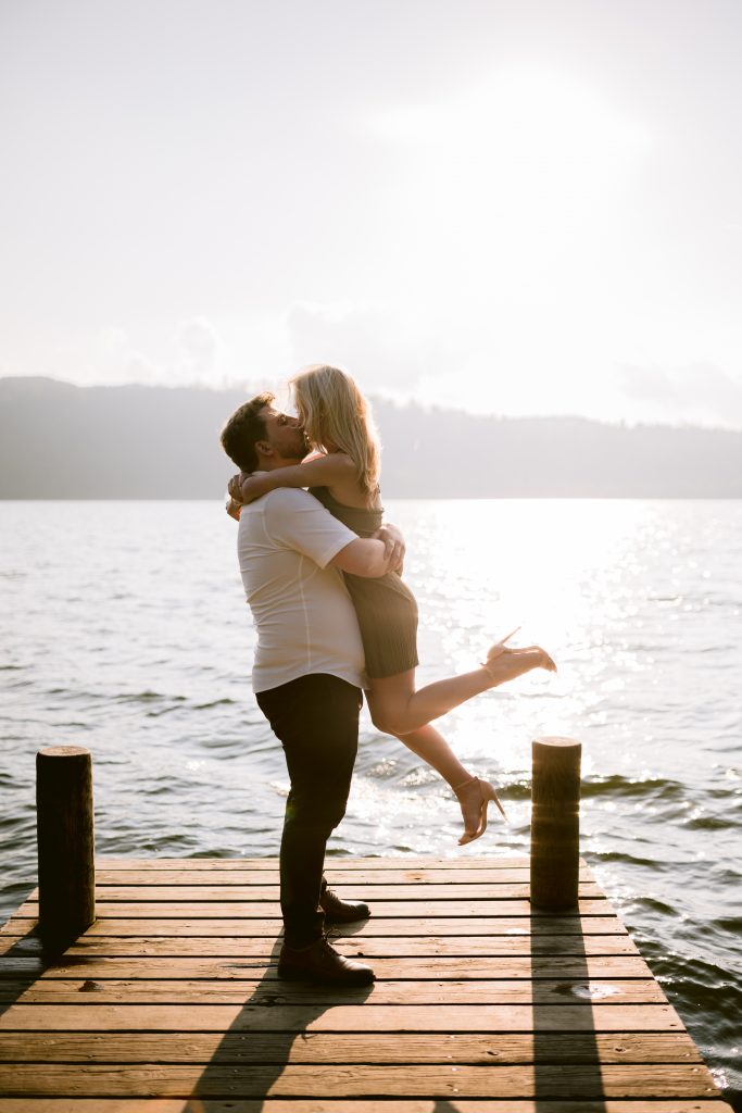 A couple hugging on a dock at sunset.