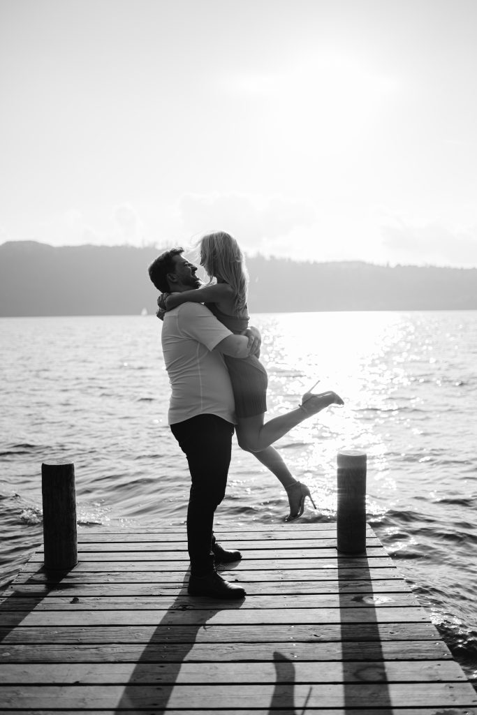 A man and woman hugging on a dock in black and white.