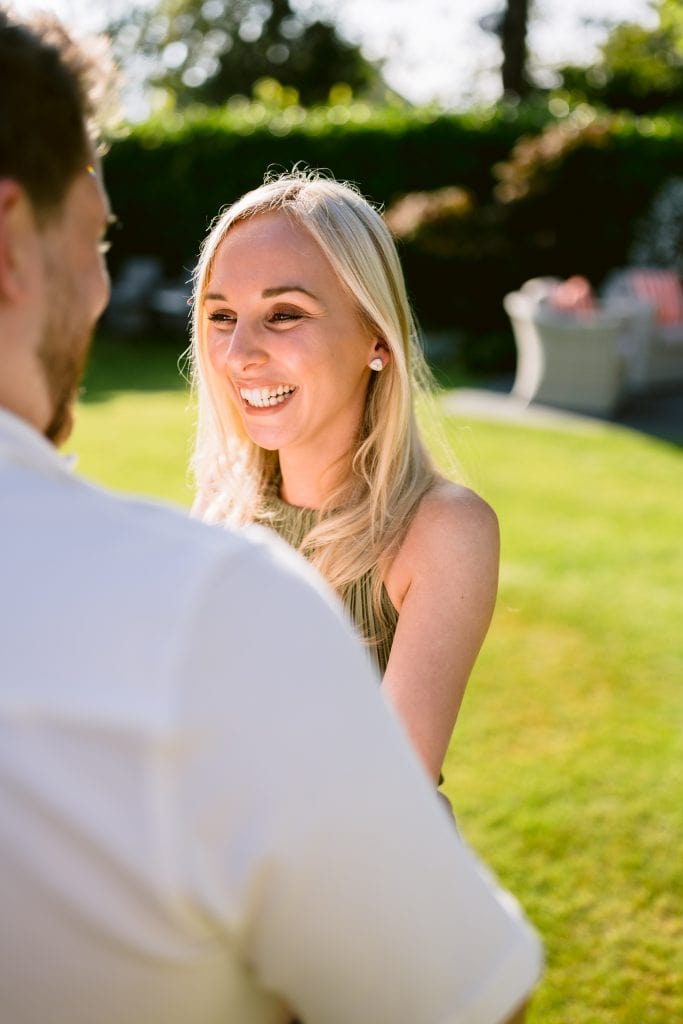 A man and woman smiling at each other in a garden.