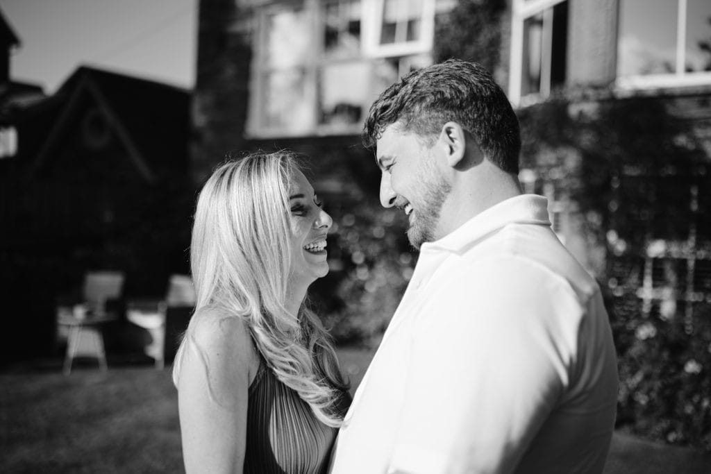 A black and white photo of a couple in front of a house.