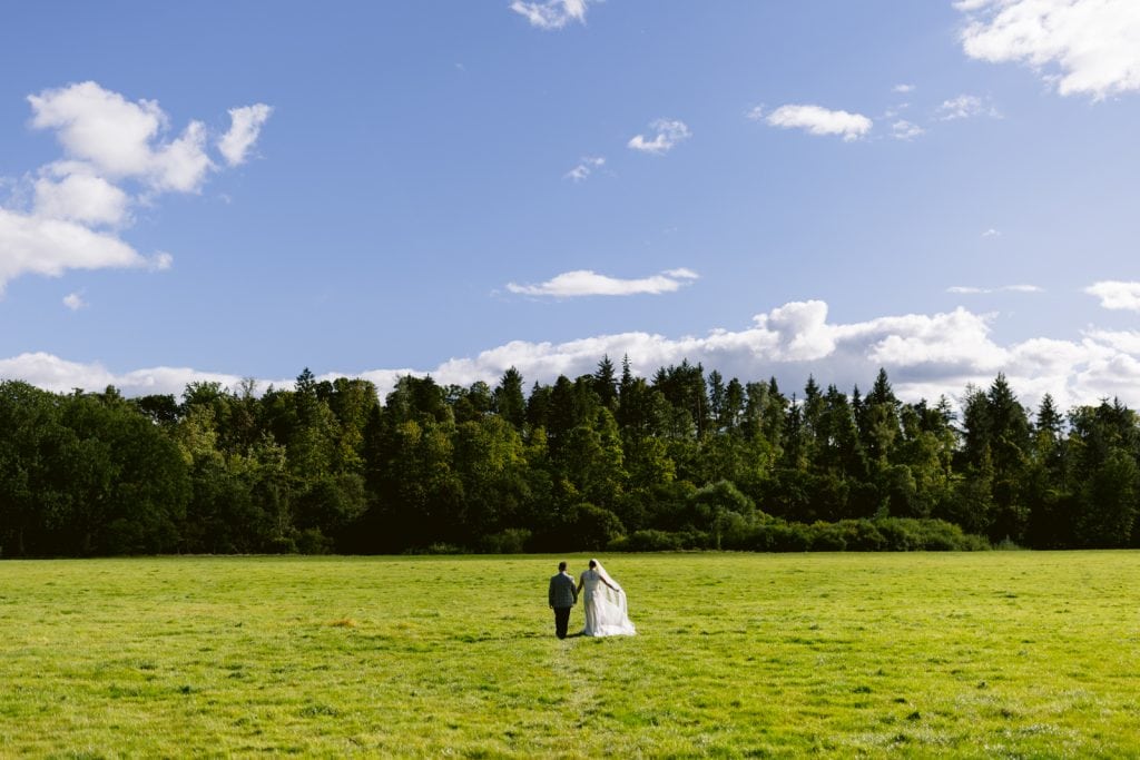 Couple walking across a field to the nearby river in lanercost