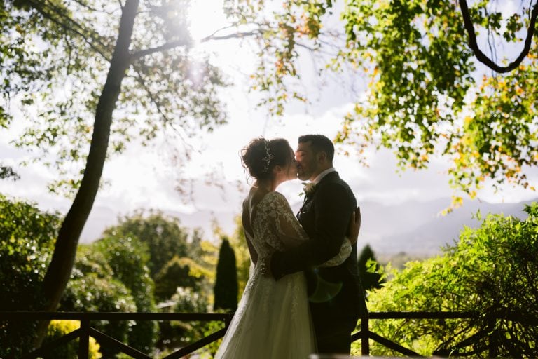 A small bride and groom kissing under a tree in the Lake District.