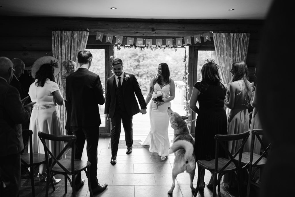An autumn elopement captured in a black and white photo, featuring a bride and groom walking down the aisle.