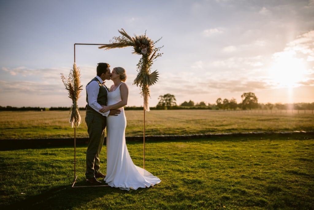 A Yorkshire couple sharing a tender kiss in an outdoor field at sunset during autumnal season.