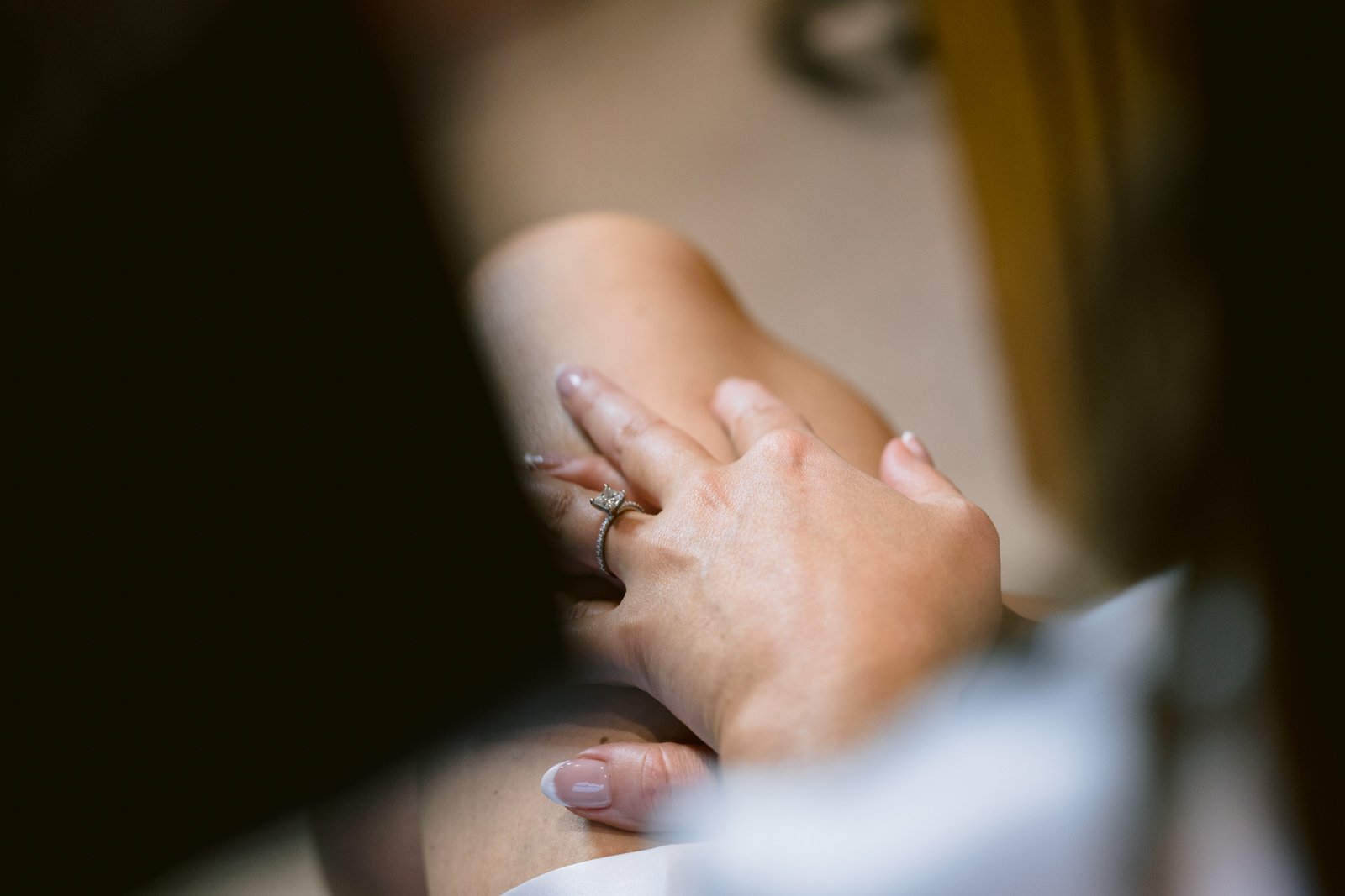 A close up of a woman's hand holding a wedding ring during winter.