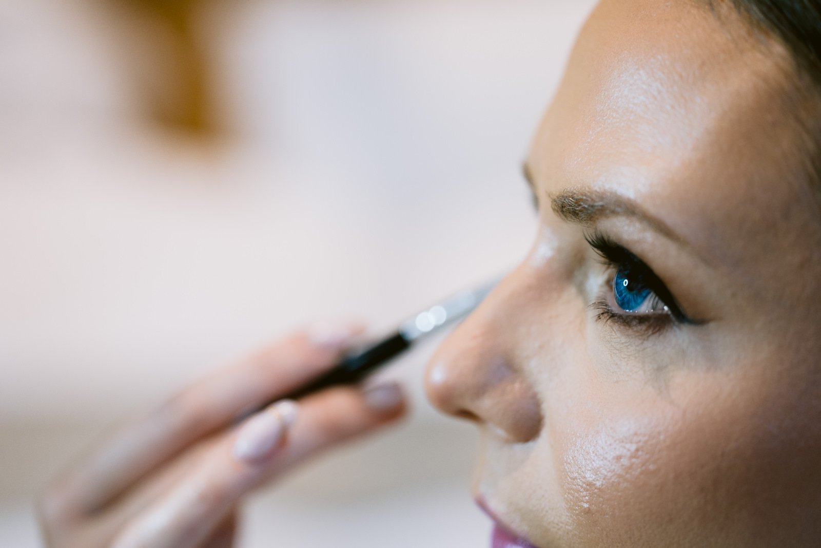 A woman is applying makeup for her Winter Wedding.