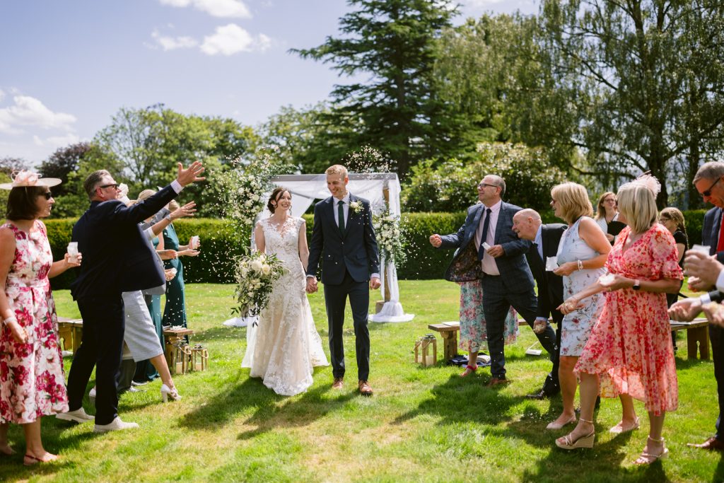 Intimate and Outdoor: A bride and groom have an intimate outdoor ceremony as they walk down the aisle at their wedding in Keswick.