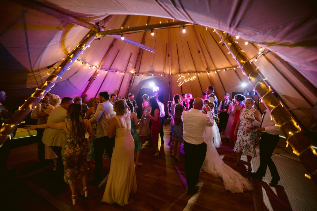 A group of people dancing in a special event tipi tent.