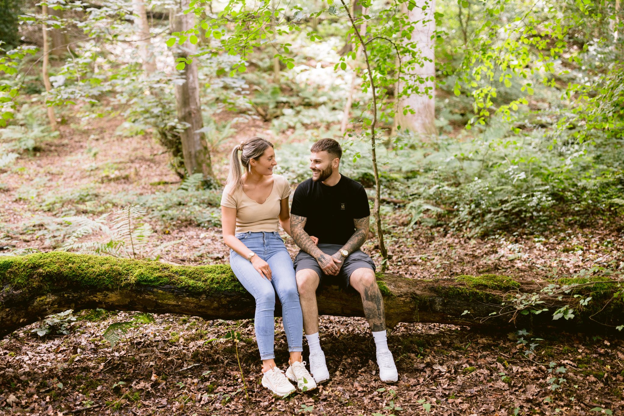 A wood couple enjoying a portrait session on a log in the woods.