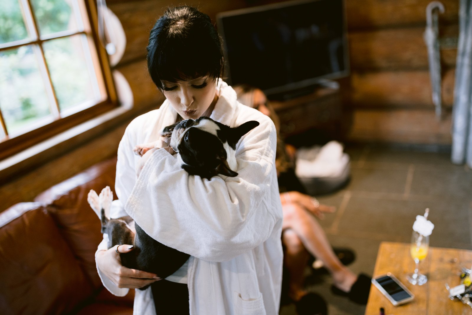 A woman in a robe holding a dog at Hidden River Cabin.