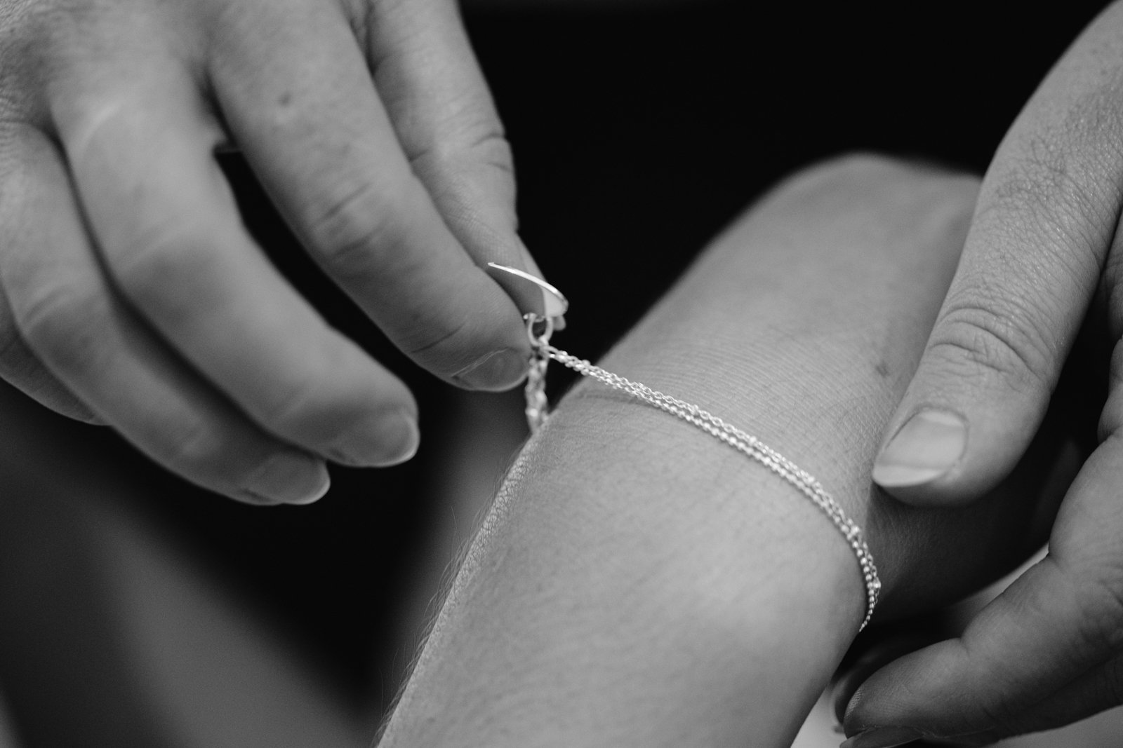 A woman is putting a bracelet on a bride's wrist at Gretna Hall Wedding.