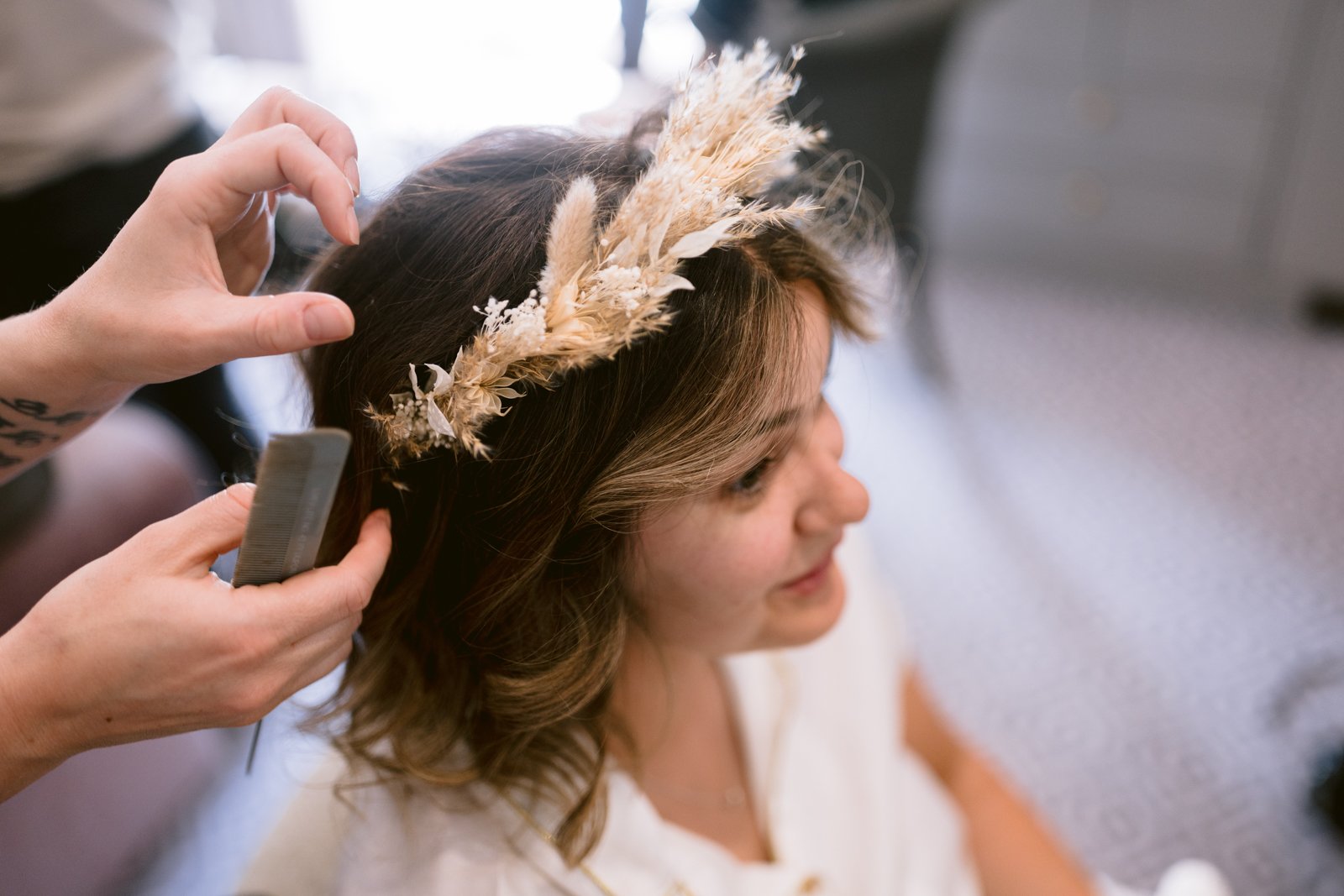 A woman getting her hair done at a wedding by a hairdresser.