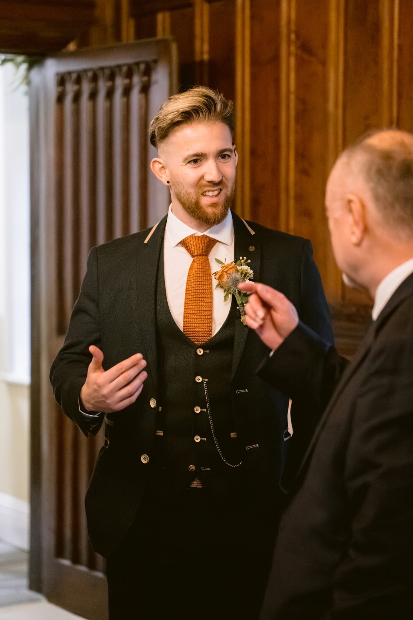 A man in a tuxedo is talking to another man in a suit at Lady Gillford's house.
