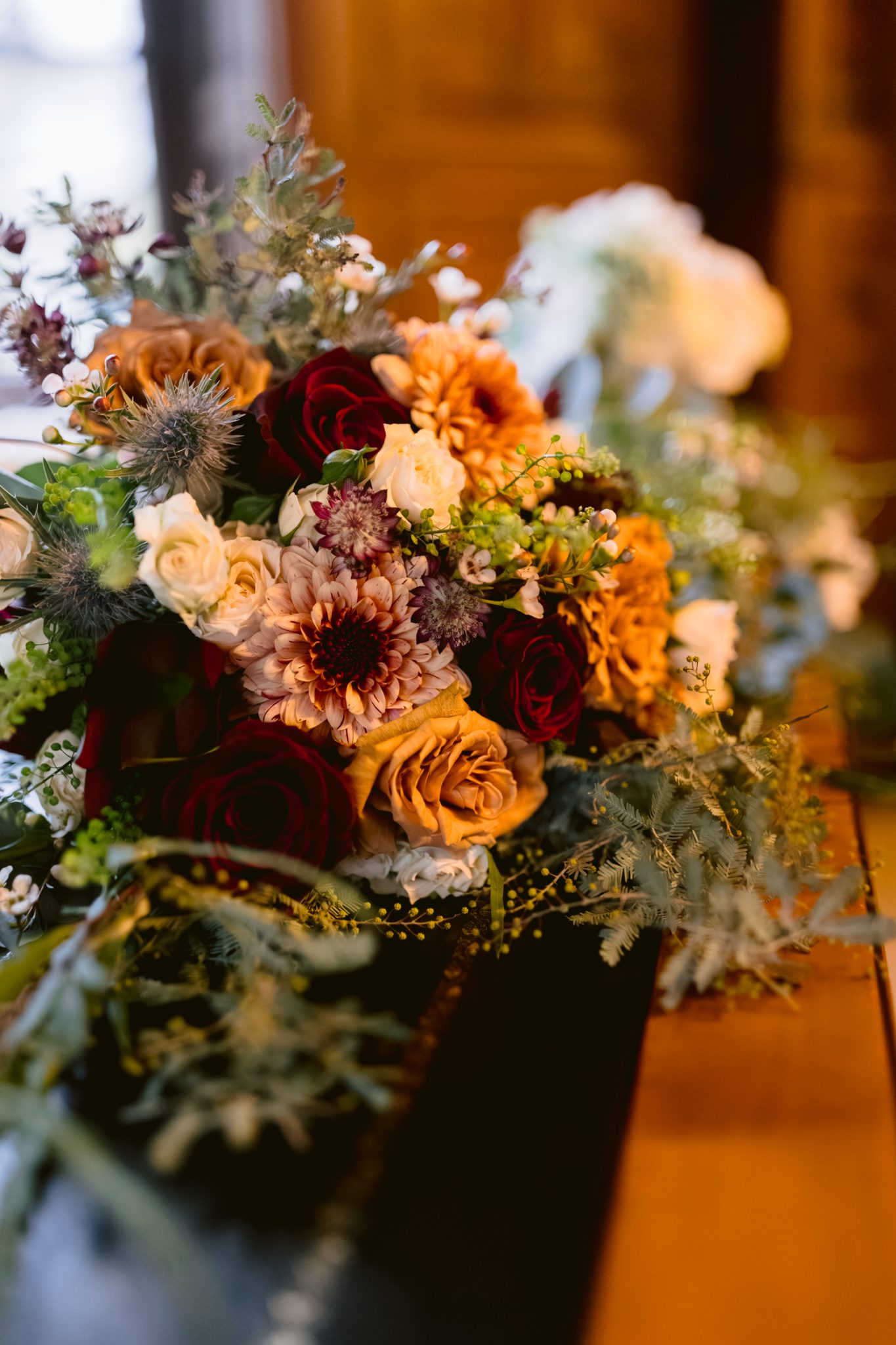 A bouquet of flowers, perfectly arranged, sitting on a wooden table at Lady Gillford's house.
