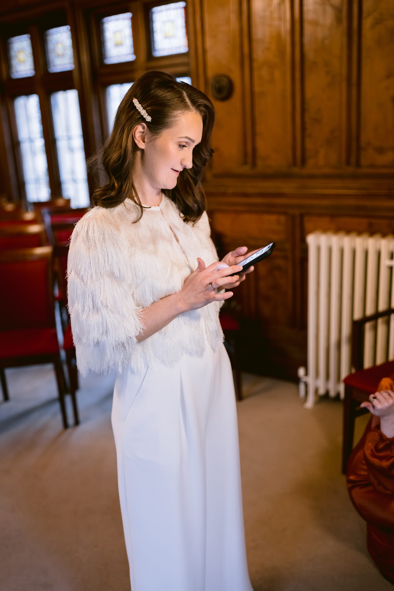 A woman, Lady Gillford, looking at her phone while sitting in a room at Winter Wedding venue.