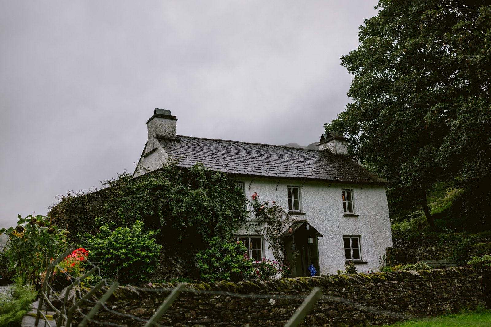 A white house in the middle of a field on a cloudy day, perfect for a summer wedding at Yew Tree Farm.