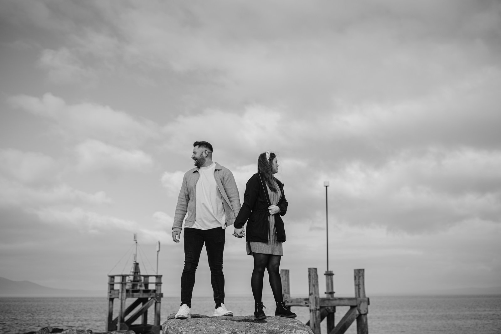 Two people standing on a pier looking out to the lake, couple Portrait Session underway.