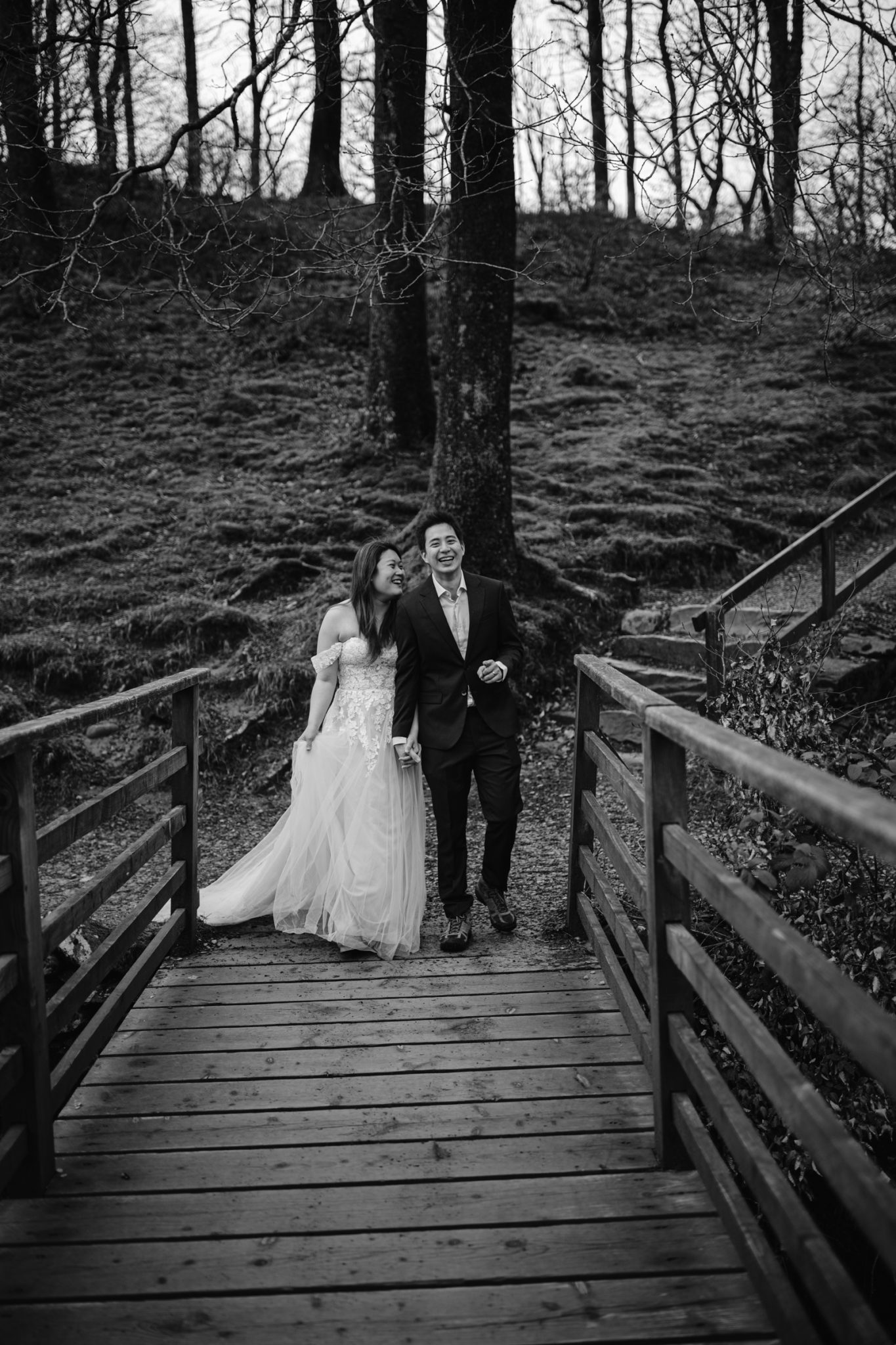 Bride and groom celebrating their wedding anniversary on a wooden bridge in a forest setting.