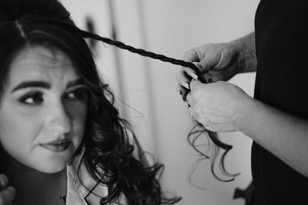 A woman gets her hair braided by another person, focusing on the braid. Black and white image.