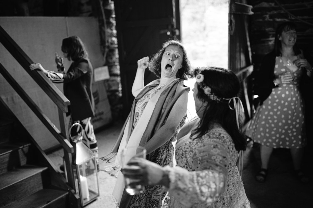 Black and white image of two women dancing energetically at an indoor event, with three other people in the background.