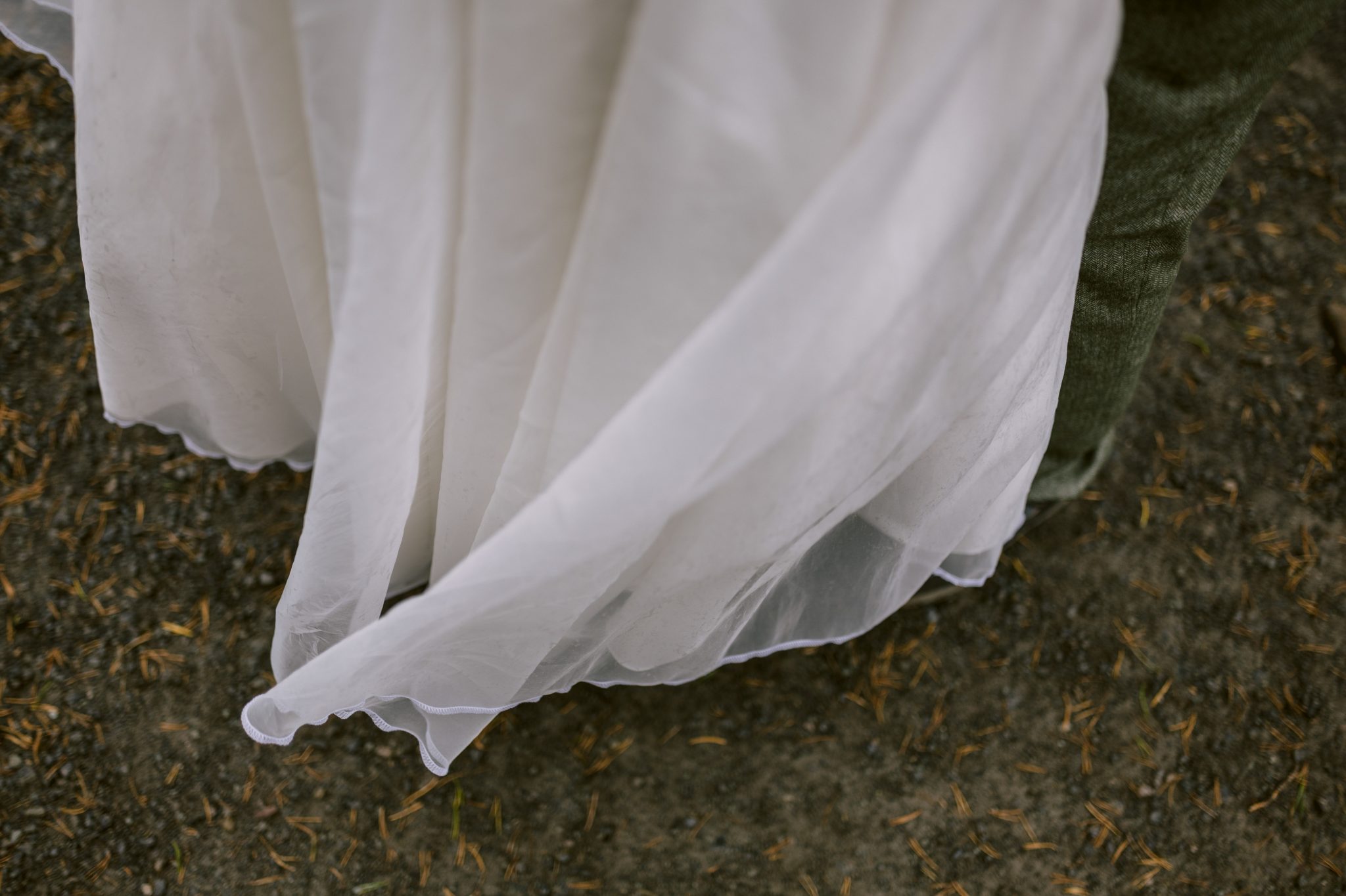 Close-up of a flowing white fabric against a textured ground, partially covering a green surface.