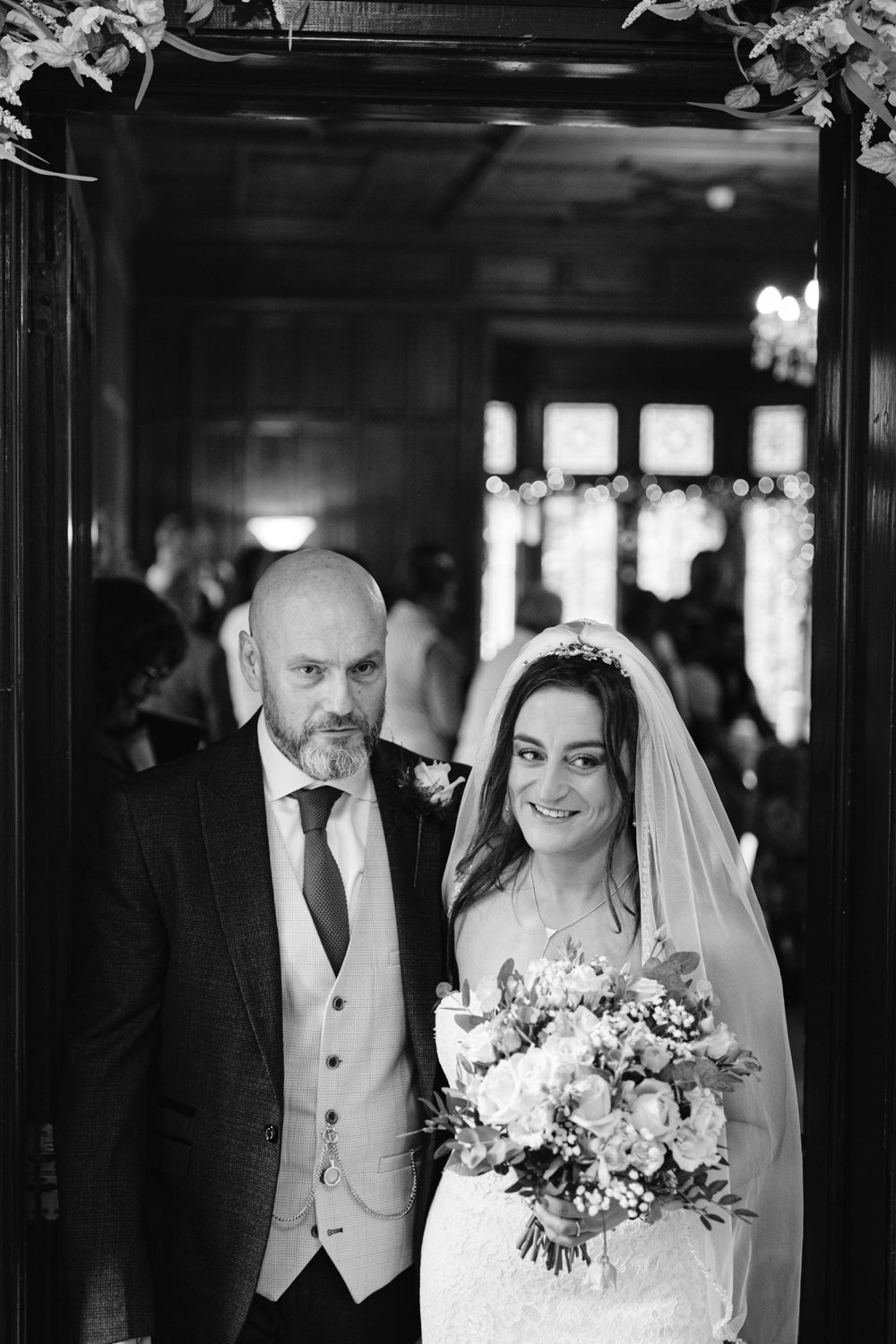 Bride and groom standing together indoors at Lady Gilford’s House, the bride holding a bouquet. The setting's dark wood paneling and decorative lights create an enchanting backdrop.