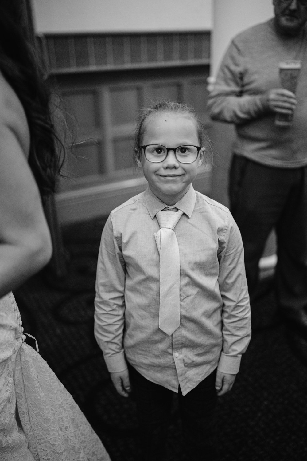 A child wearing glasses and a tie stands indoors at Lady Gilford’s House, smiling at the camera.