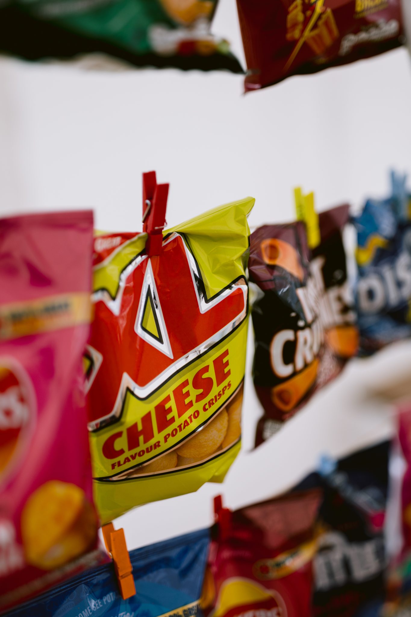 Close-up of diverse flavored potato chip bags, including cheese flavor, clipped in a row, reminiscent of a delightful snack table at a Summer Marquee Wedding in the gardens of Kirklinton Hall.