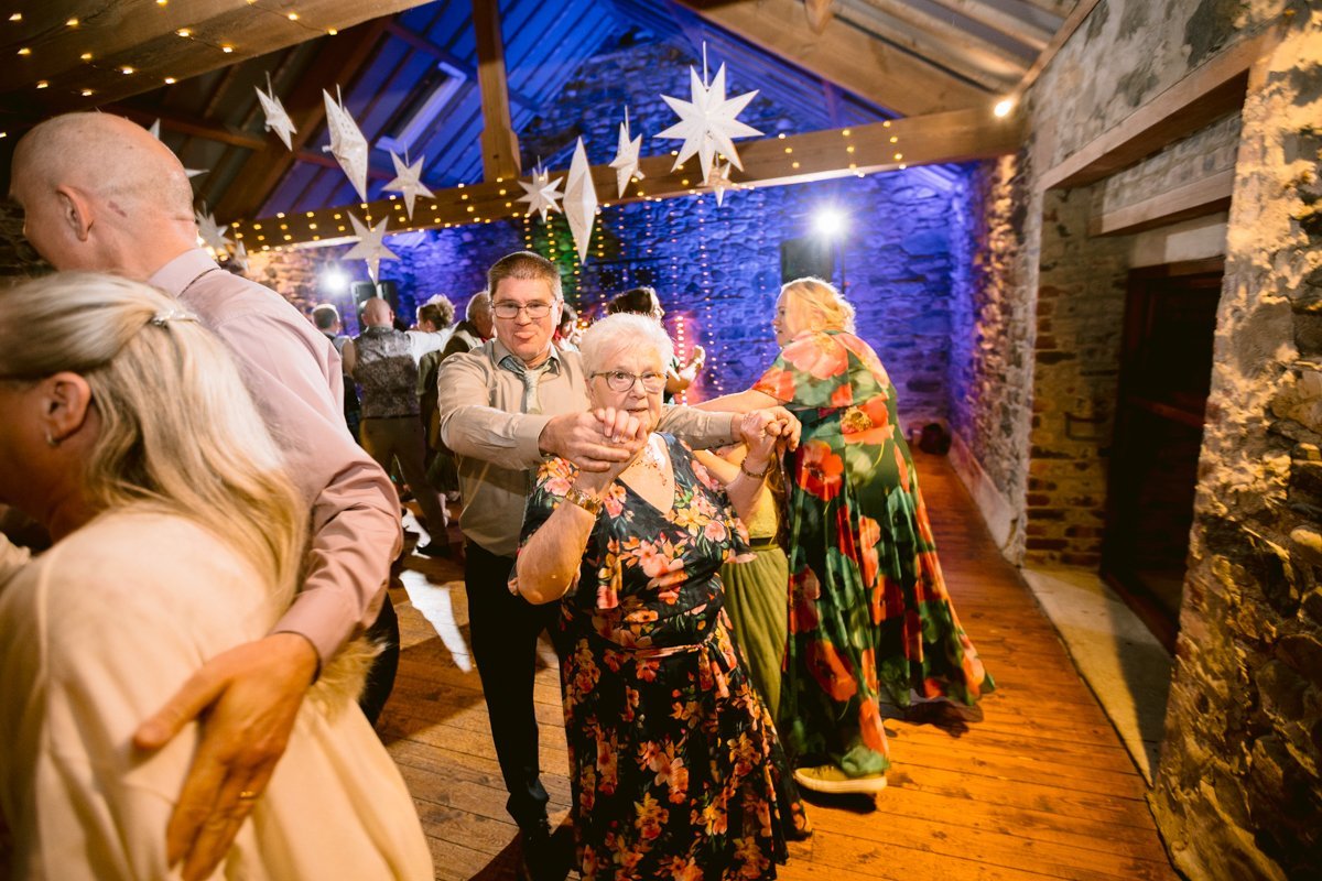 People dancing in a warmly lit, rustic venue called Low Hall, with wooden floors and star decorations hanging from the ceiling.