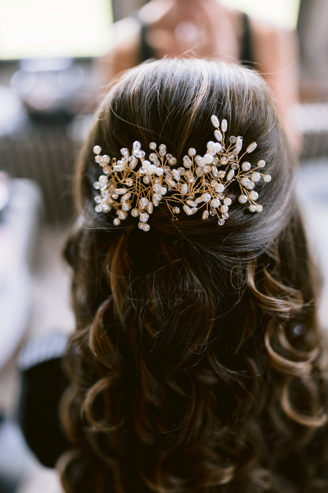 A woman's brown, wavy hair styled half-up with a decorative gold hairpiece featuring pearls and beads—perfect for an August summer wedding at Armathwaite Hall.