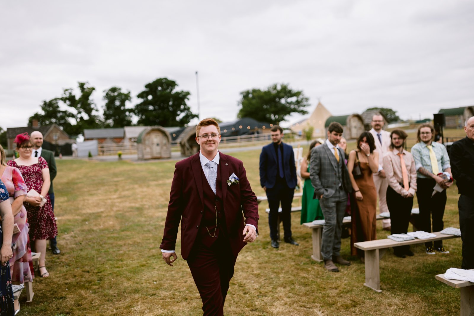 A man in a suit walking down a field, perfect for a rustic farm wedding in Shrewsbury.
