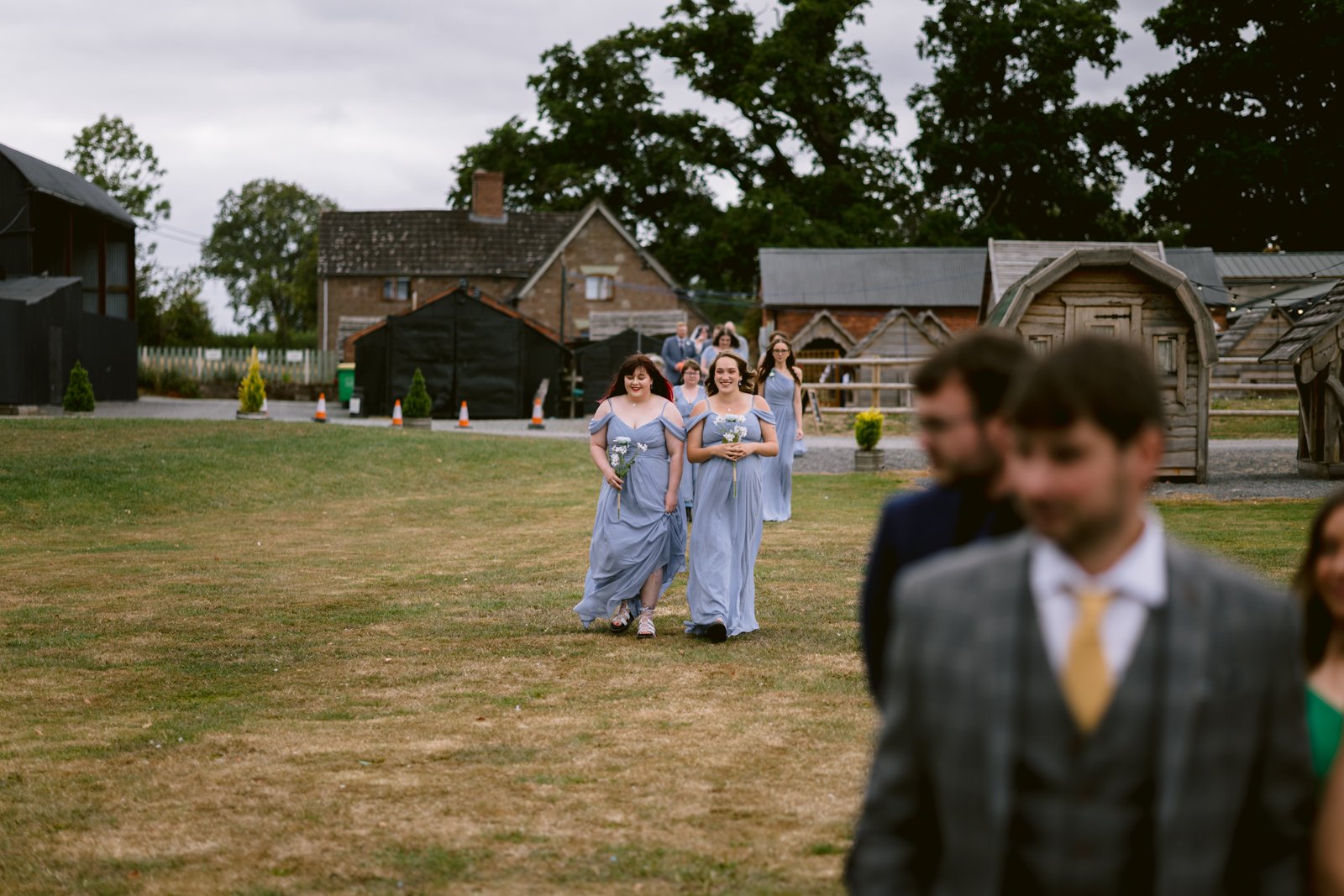 A group of people walking in a field at a rustic Stanford Farm wedding near Shrewsbury, enjoying an LGBT+ friendly celebration.