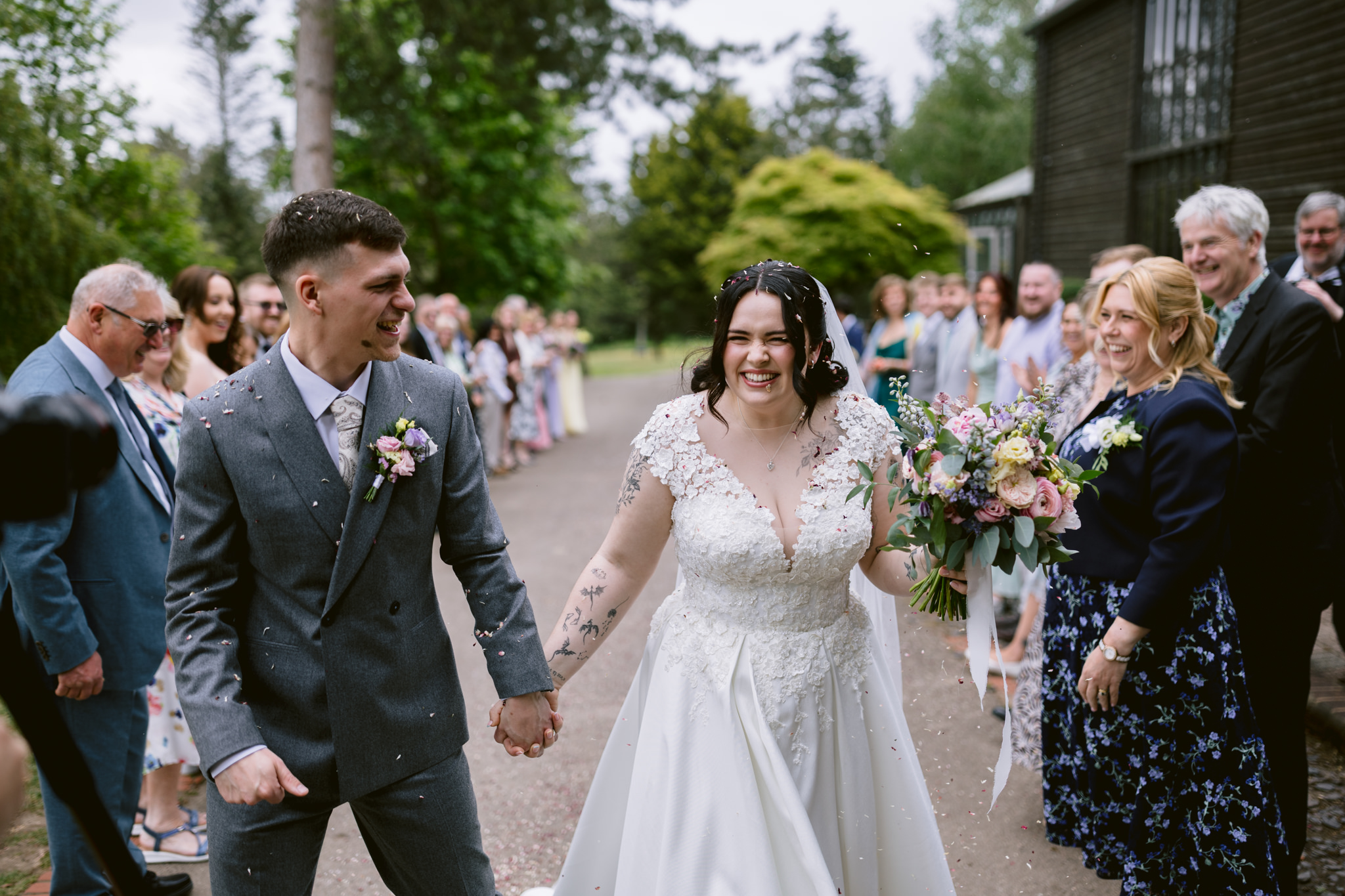 Newlyweds walk hand-in-hand through a shower of confetti, smiling, at their beautiful Essendon Country Club wedding—captured perfectly in timeless wedding photography.