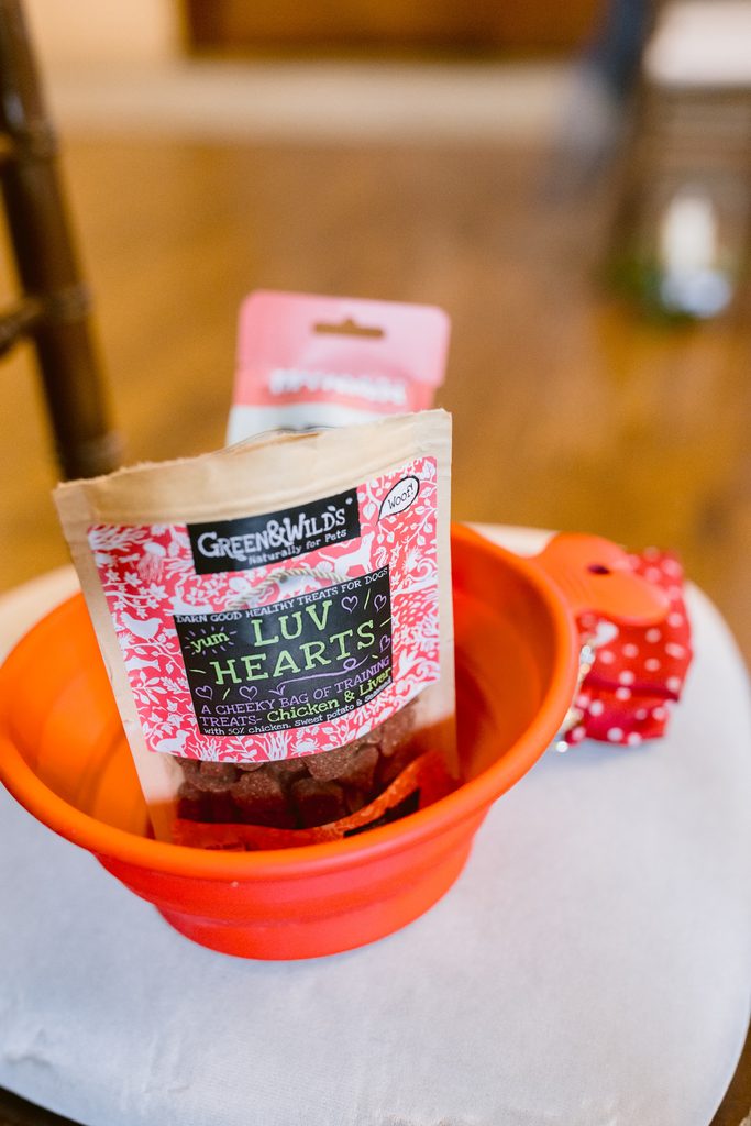 A packet of Green & Wild’s Luv Hearts dog treats in a collapsible orange bowl with a red polka dot accessory nearby, reminiscent of a late summer wedding at The Maynard or an afternoon stroll through Padley Gorge.