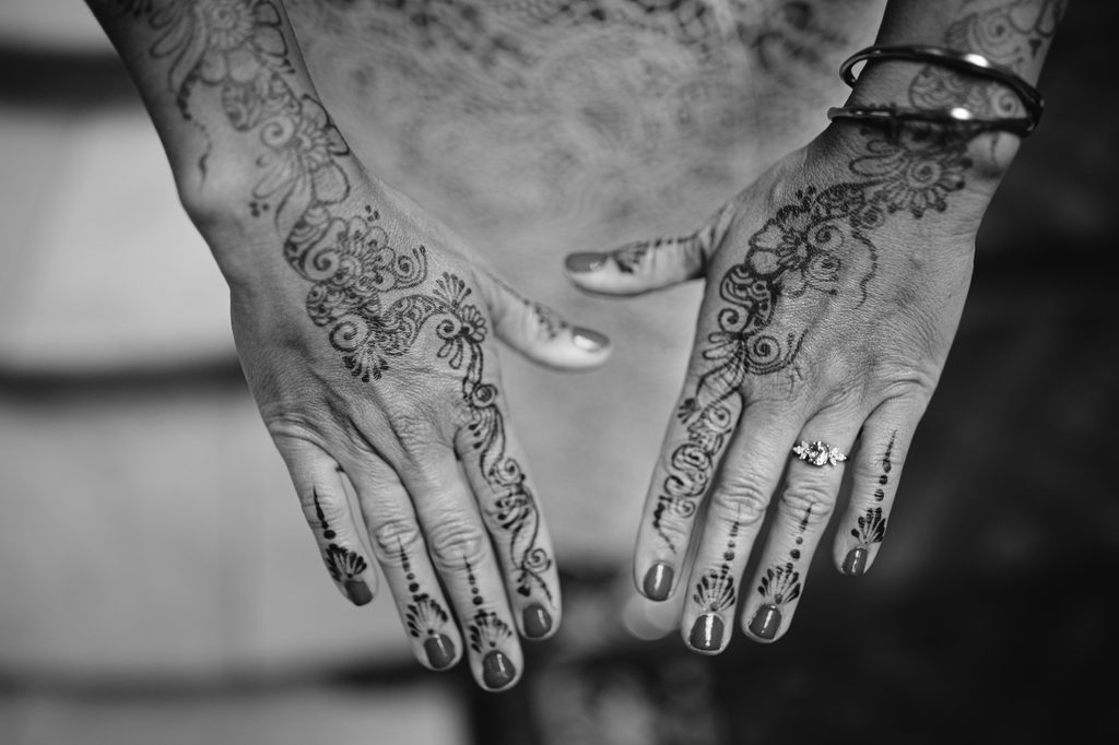 Close-up of two hands featuring intricate henna designs and a diamond ring, captured at an intimate Sheffield wedding.